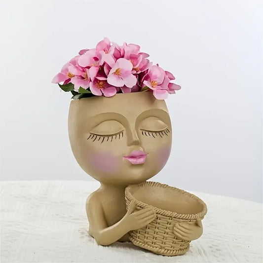 Pot de fleur original pour plantes en forme de visage artistique, tenant un panier, avec des fleurs roses sur le dessus