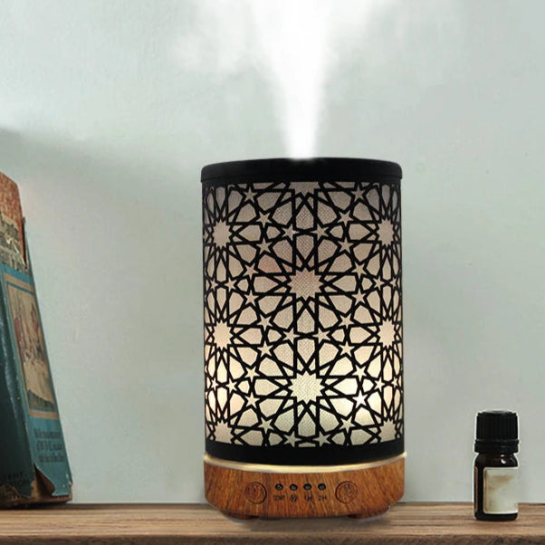 Diffuseur huiles essentielles marocain élégant avec motif incrusté, émettant une brume apaisante et accompagné d'une huile essentielle