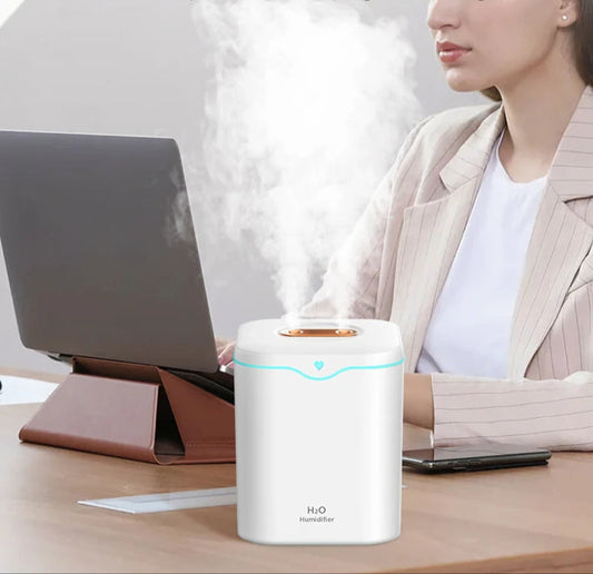 Diffuseur d'huiles essentielles HIMISTE blanc diffusant de la vapeur près d'un ordinateur, idéal pour acheter diffuseur aromatique.