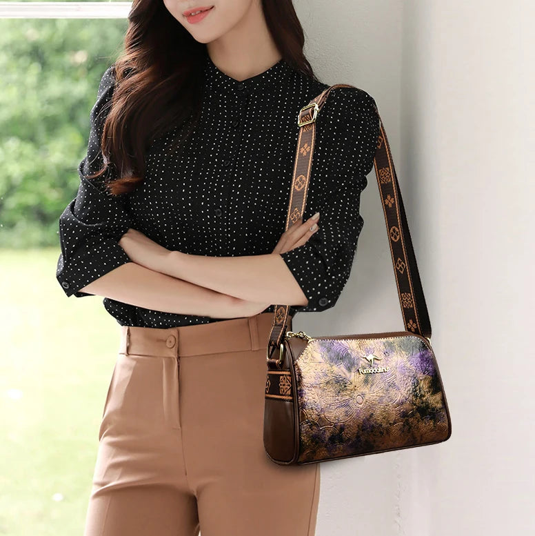 Sac bandoulière en cuir souple pour femme, élégant et pratique, avec motifs colorés, porté par une femme en blouse noire à pois