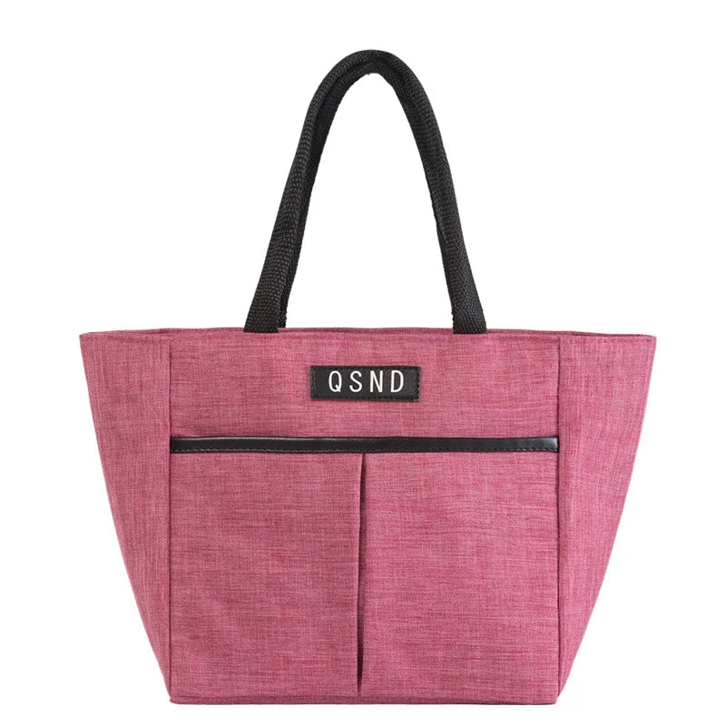 Sac isotherme portable en tissu rose avec poches avant et anses noires pour un transport pratique des aliments