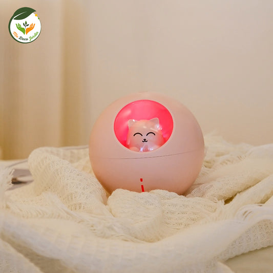 Diffuseur d'huiles essentielles design en forme de sphère rose, avec un éclairage doux et un petit chat mignon à l'intérieur