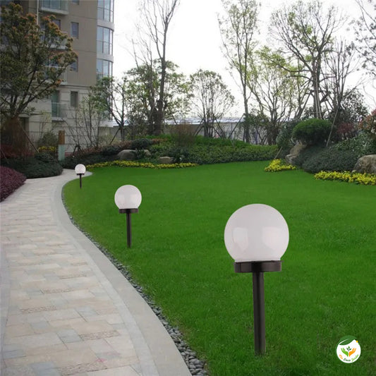 Lampe LED jardin élégante avec globe blanc éclairant le chemin dans un jardin bien entretenu, parfaite pour l'extérieur