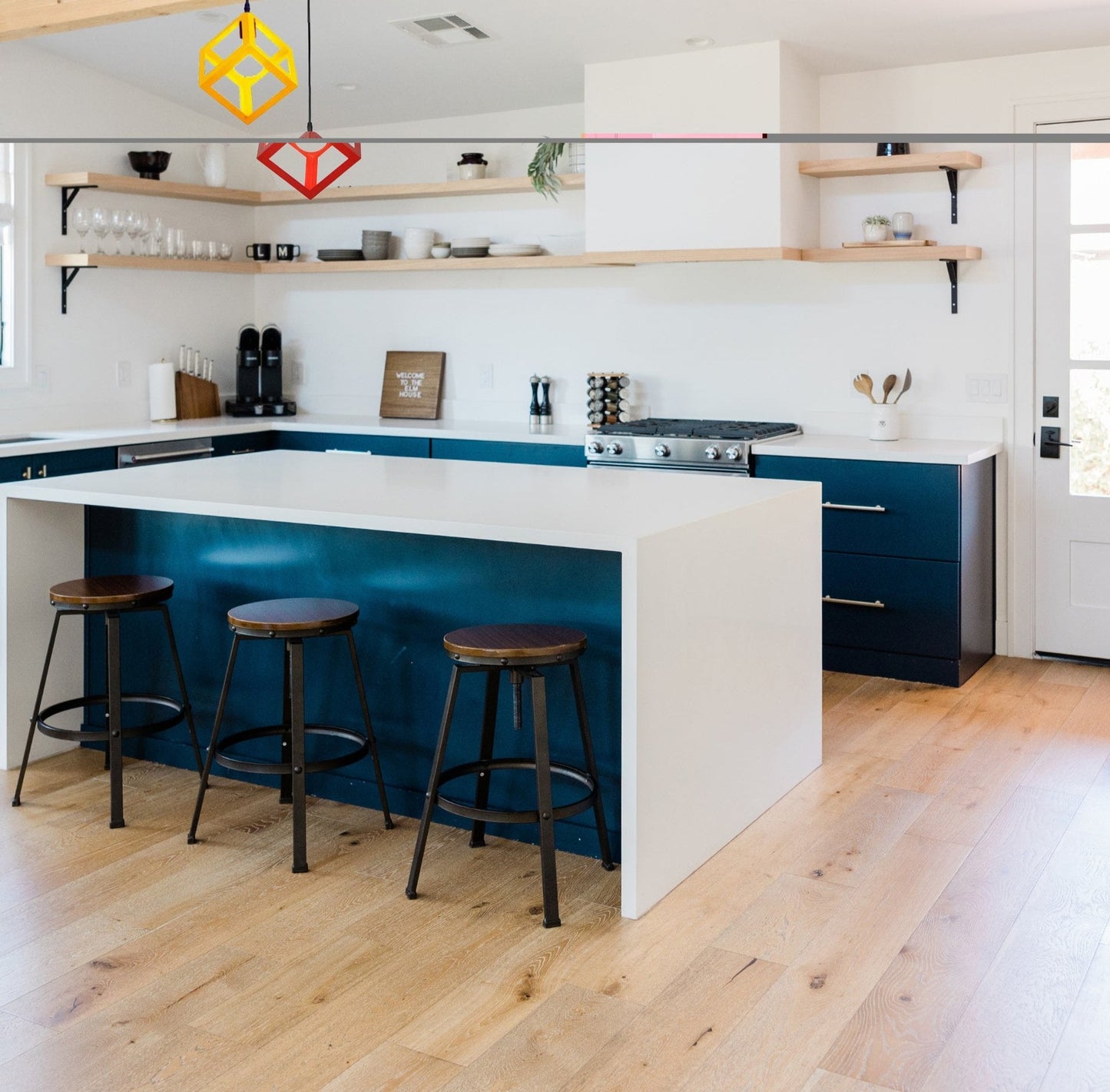 Plafonnier LED cuisine moderne suspendu au-dessus d'un îlot de cuisine blanc avec des tabourets en bois.
