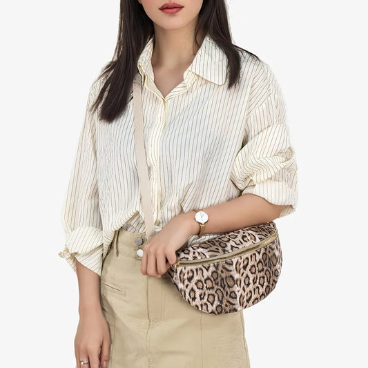 Femme portant un sac banane tendance femme en motif léopard, associé à une chemise à rayures et une jupe beige.