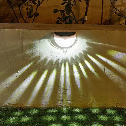Applique murale solaire sur un mur, projetant des lumières colorées en éventail sur le sol vert