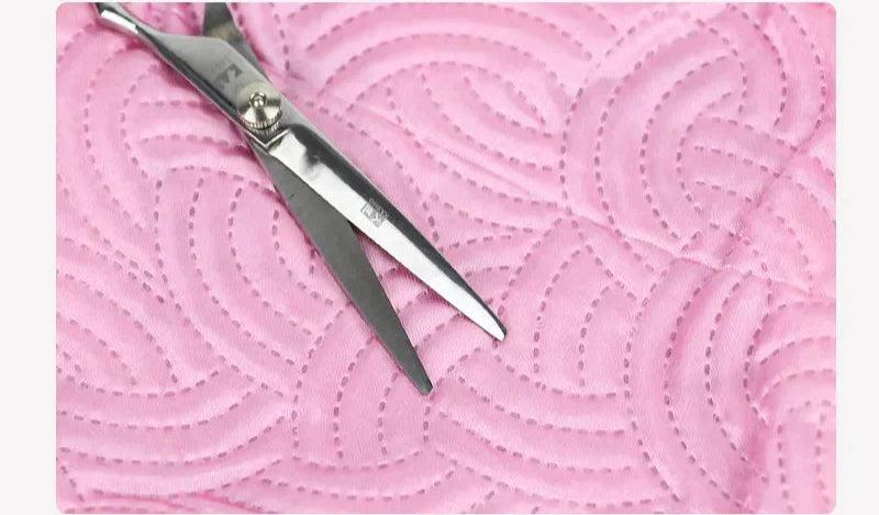 Bonnet chauffant pour cheveux en tissu rose, décoré avec un motif texturé, à côté de ciseaux