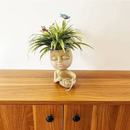 Pot de fleur original pour plantes avec un visage artistique et une verdure stylisée sur un meuble en bois