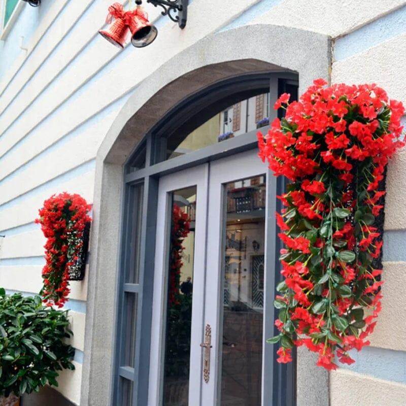Fleurs artificielles haut de gamme en pot rouge, accrochées à une façade, apportant une touche colorée et élégante au jardin