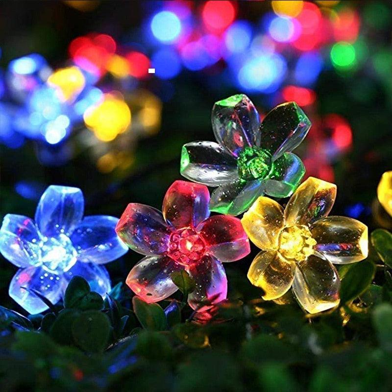 Guirlande lumineuse jardin LED avec fleurs éclatantes brillantes, créant une ambiance festive et colorée à l'extérieur.