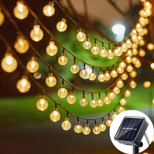 Guirlande lumineuse LED solaire suspendue, illuminant un espace extérieur avec des boules lumineuses scintillantes, idéale pour la décoration
