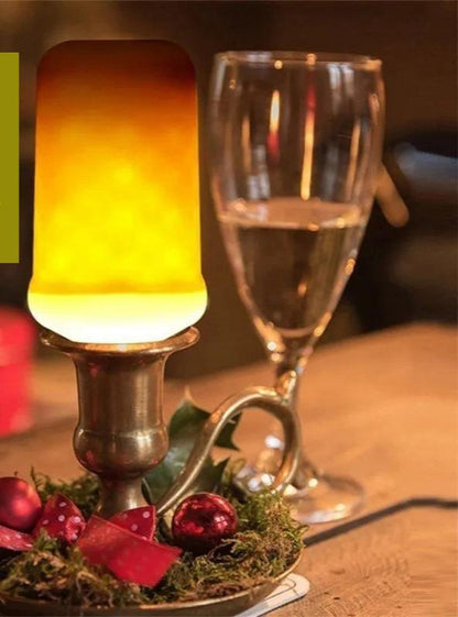 Ampoule imitation flamme éclairant une bougie en métal sur une table, avec un verre à côté pour une ambiance chaleureuse