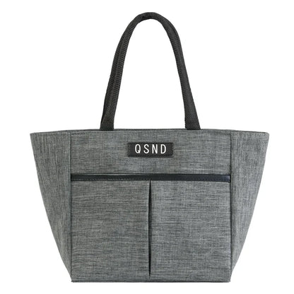Sac isotherme portable en tissu gris avec poignées noires et poches avant, idéal pour le transport de denrées périssables