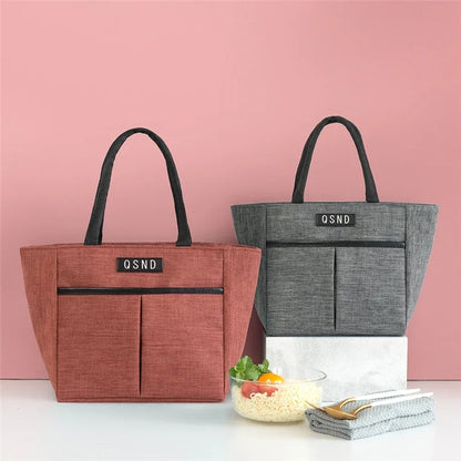Sac isotherme portable en tissu, disponible en rouge et gris, idéal pour le transport des repas et collations.