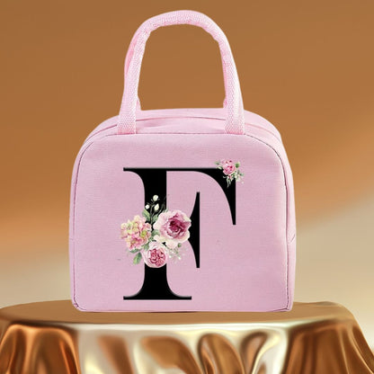 Sac isotherme rose avec un motif floral et la lettre F en noir, idéal pour conserver vos repas au frais