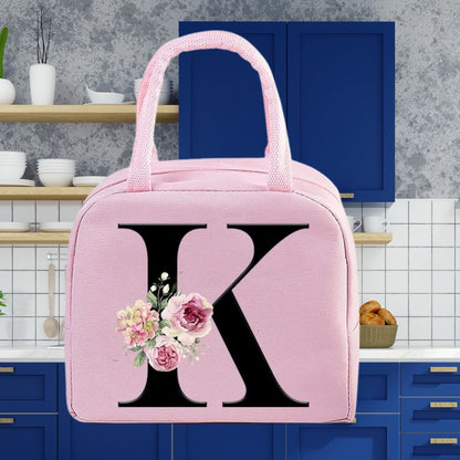 Sac isotherme rose avec une lettre K et des fleurs décoratives, parfait pour le déjeuner ou les pique-niques.