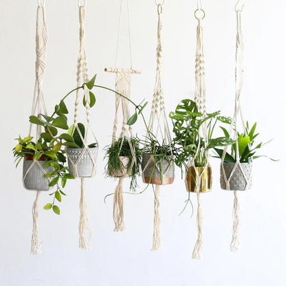 Support pot de fleur suspendu en macramé avec plusieurs plantes vertes dans des pots décoratifs, créant une ambiance naturelle et élégante
