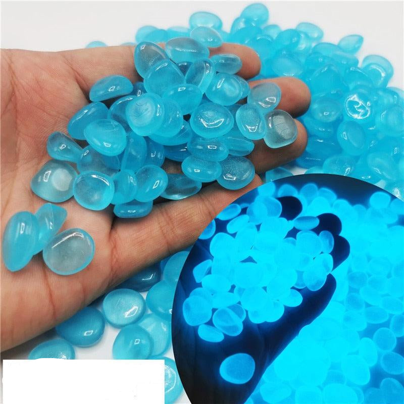 Main tenant des pierres scintillantes decoratives bleu lac, émettant une lueur douce dans l'obscurité pour des ambiances éclairées