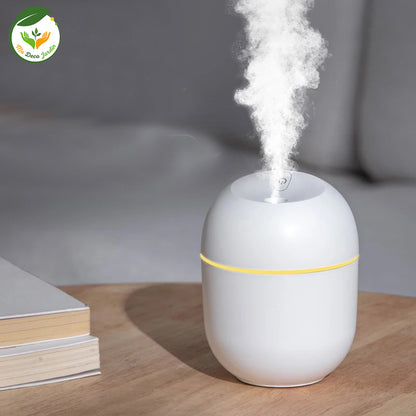 Diffuseur huiles essentielles blanc, émettant une vapeur aromatique, posé sur une table en bois avec des livres.