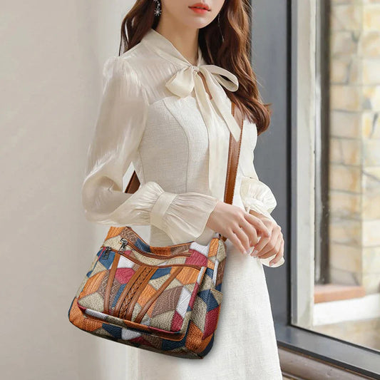 Sac vintage femme en cuir avec un design élégant et coloré, porté par une femme en robe chic près d'une fenêtre